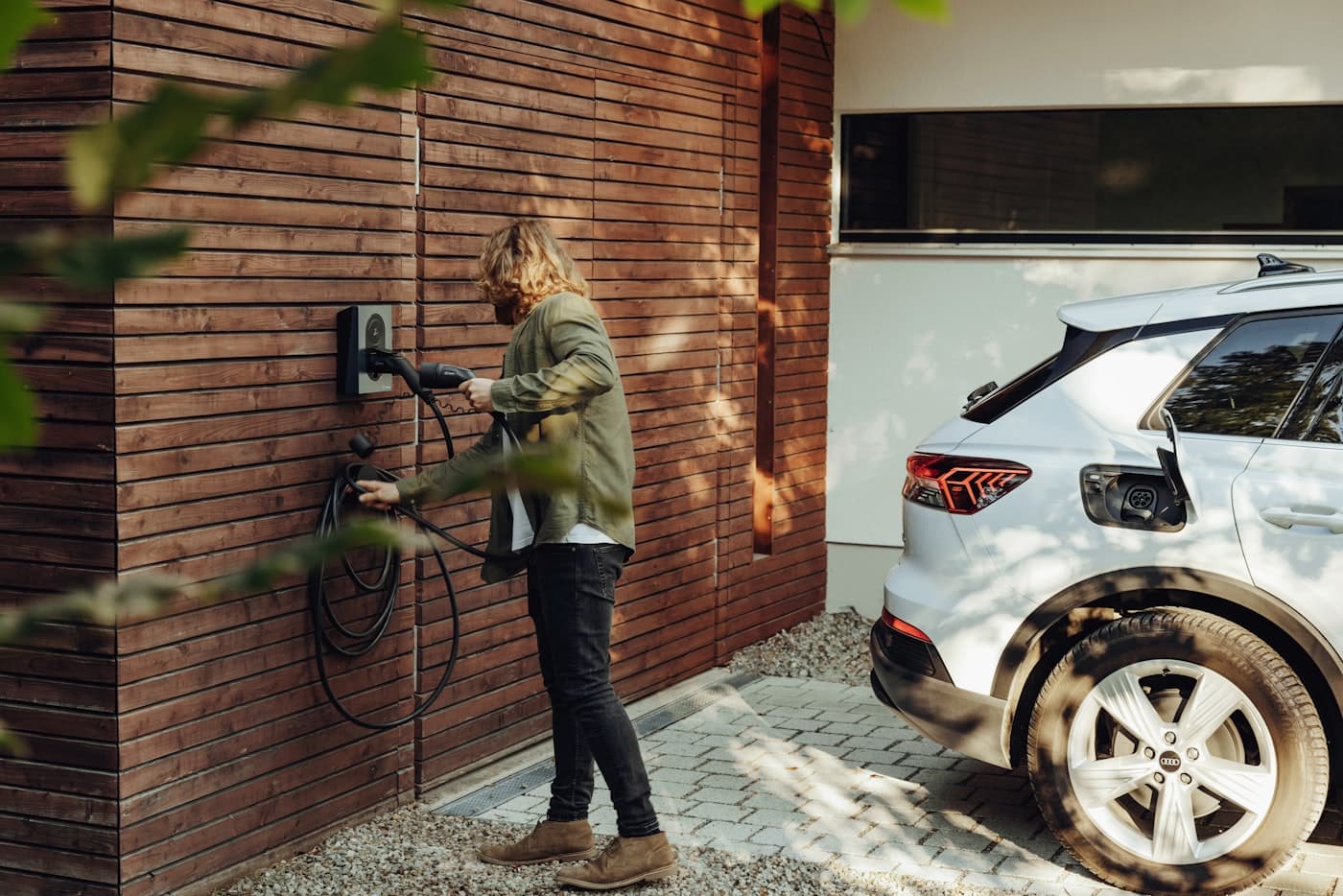 Jemand lädt sein E-Auto an der Wallbox zuhause